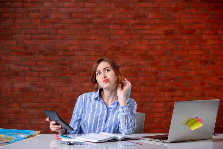 front view thinking travel agent sitting her working place with laptop working with calculator map agency service assistant manager ticket operator world global