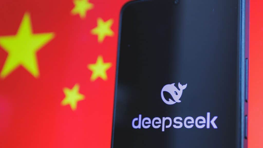 Celular exibindo logo DeepSeek em frente a uma bandeira da China desfocada, ilustrando a preocupação com dados e a DeepSeek Proibida na Microsoft