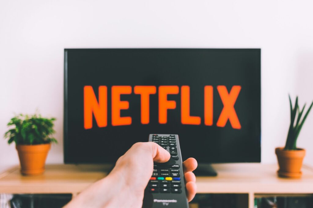 Imagem mostra o logo estilizado da Netflix e controle remoto, referência à política de bloqueio do compartilhamento de senha