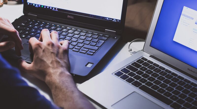imagem de pessoa digitando com dois laptops