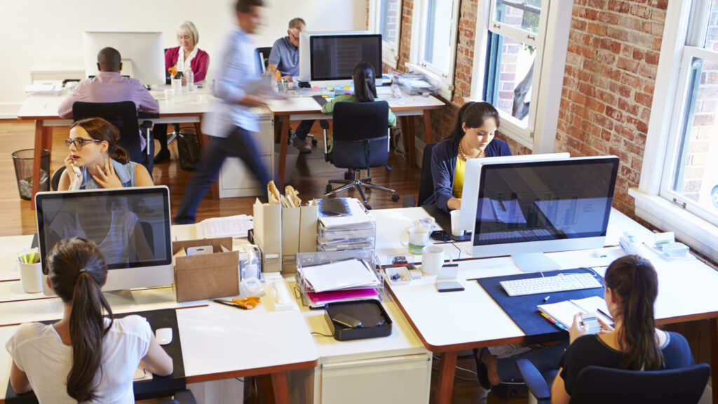 Freelancers ganham mais com IA no Reino Unido 3 Escritório movimentado com iMacs e pessoas trabalhando