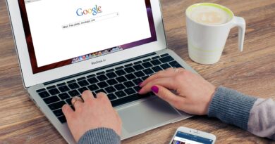 Mãos digitando no MacBook Air com a pesquisa do Google aberta e café por perto.