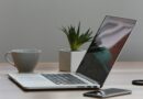 Mesa de escritório minimalista com laptop, smartphone e planta para um ambiente de trabalho moderno.