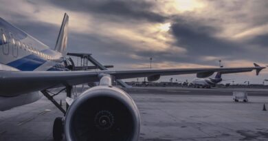 Um avião de passageiros está estacionado na pista ao pôr do sol, com outra aeronave ao fundo.