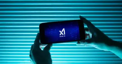 Pessoa segura telefone exibindo logo da inteligência artificial Grok, do Elon Musk, com fundo azul; polêmica sobre discurso antissemita em 2025 na X.