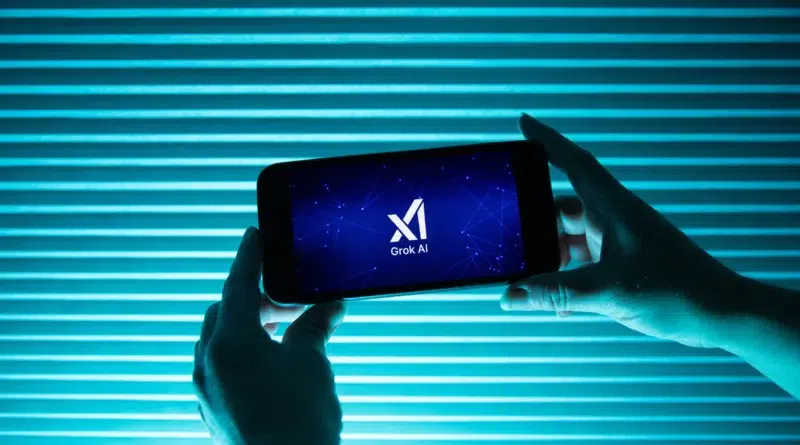 Pessoa segura telefone exibindo logo da inteligência artificial Grok, do Elon Musk, com fundo azul; polêmica sobre discurso antissemita em 2025 na X.