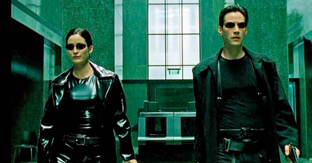 7 melhores filmes sobre hackers segundo o IMDb 10 Cena icônica do filme Matrix com Neo na frente de códigos digitais, destaque para filmes sobre hackers e cultura pop