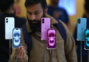 Homem observa iPhones em loja mostrando concorrência tecnológica, possível alvo das novas intervenções britânicas sobre Apple e Google no Reino Unido