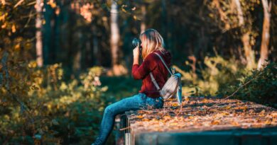 Young woman takes photos in a vibrant forest setting, embracing nature.