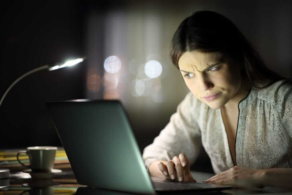 Golpes com CPF na nota: 5 sinais e como evitar 9 Pessoa desconfiada analisa um notebook com suposta restituição da nota