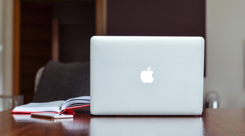 MacBooks pegam virus: A clean and modern workspace featuring a laptop, book, and smartphone on a wooden table.